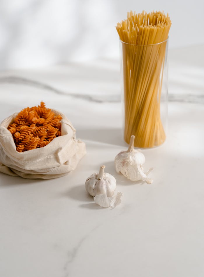 High-quality close-up of raw pasta and garlic on a marble surface, ideal for food-themed projects.