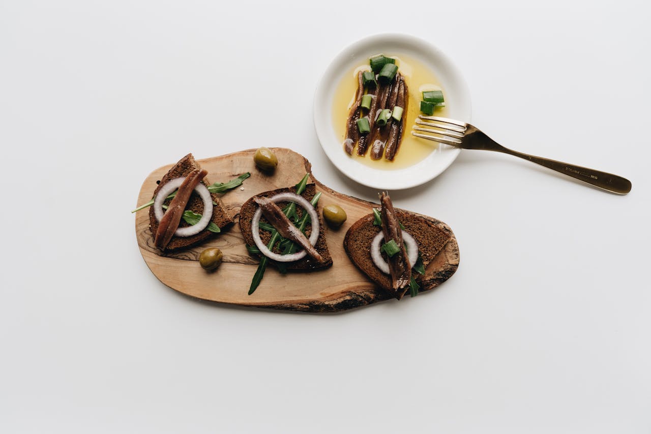 Appetizing flatlay of anchovy tapas with olives and onions, perfect for food photography.